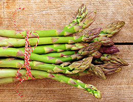 A bunch of asparagus tied with red and white string.