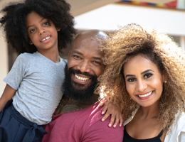 A smiling man, woman and child.